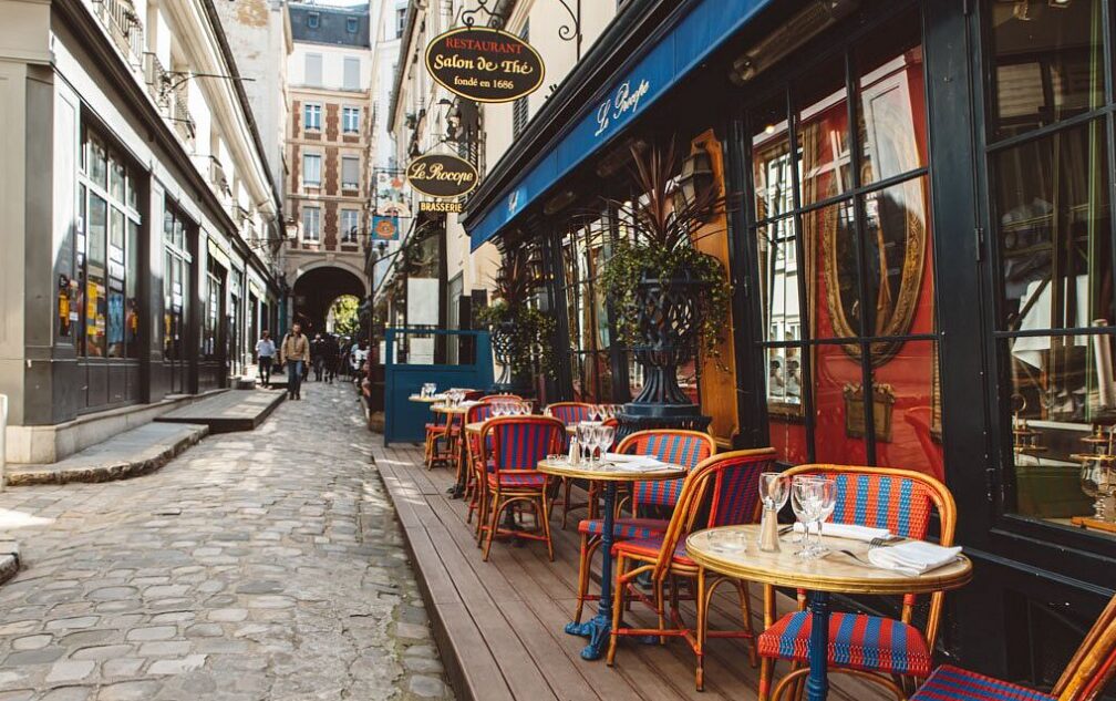 Dónde comer en París by ZapatillasPorElMundo. Calle parisina con sus icónicas sillas de rallas rojas donde podrás tomarte un café