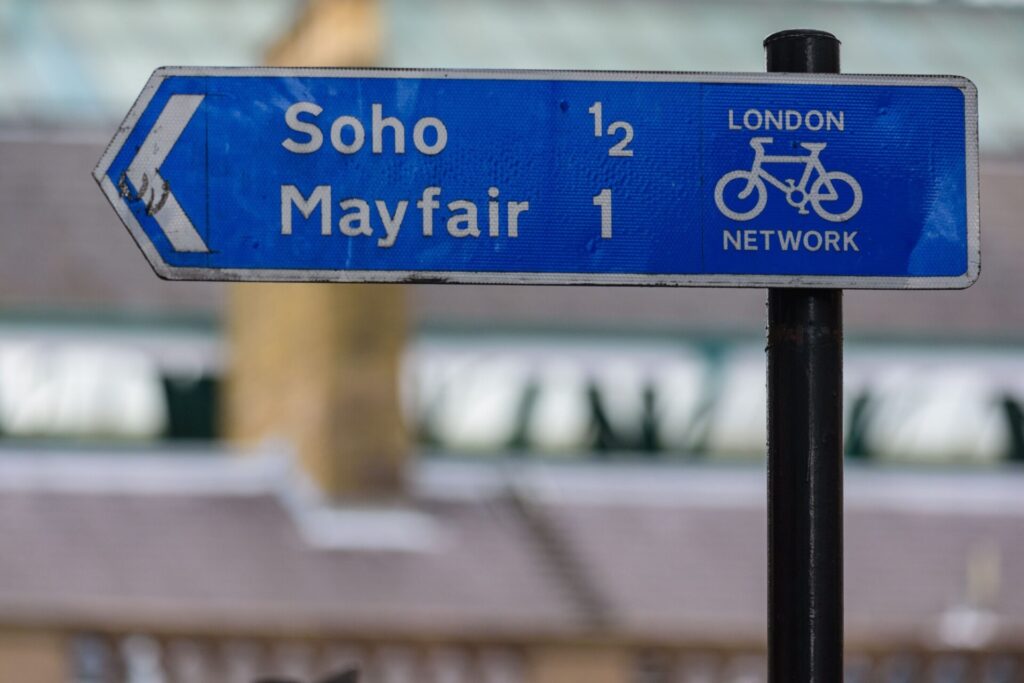 LONDRES EN UN DÍA: una parada para reponer fuerzas y a seguir.   A signpost in central London directs cyclists towards Soho and Mayfair along the London Network