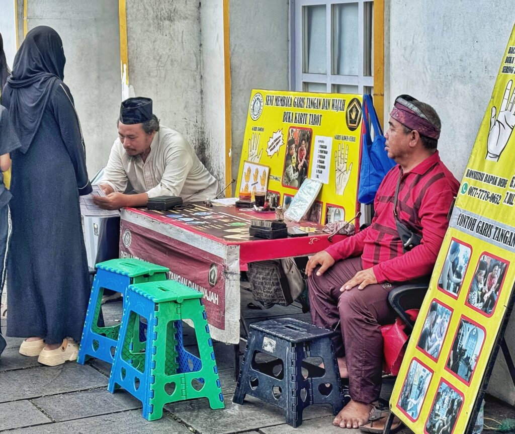 Mercado local con un puesto donde un hombre le lee la mano a una mujer en Indonesia