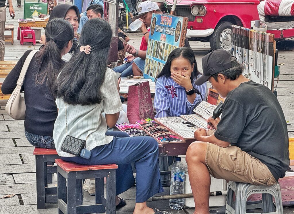 Mujer en un puesto en un mercado en Indonesia, se tapa la boca cuando mira a la cámara