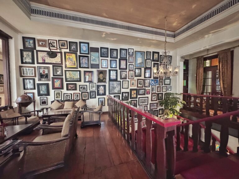 Interior de una cafetería en Yakarta con pared repleta de fotografías enmarcadas y muebles de madera