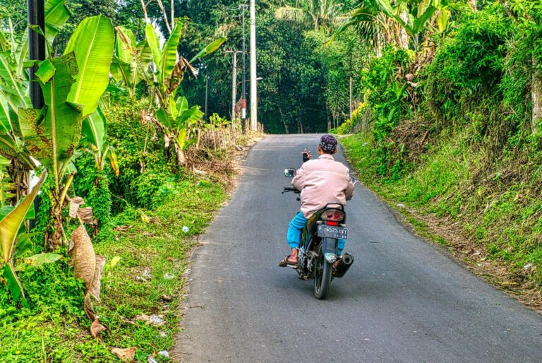 a man riding a motorcycle in a rural road