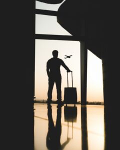 Hombre mirando a un avión desde un aeropuerto junto a su maleta